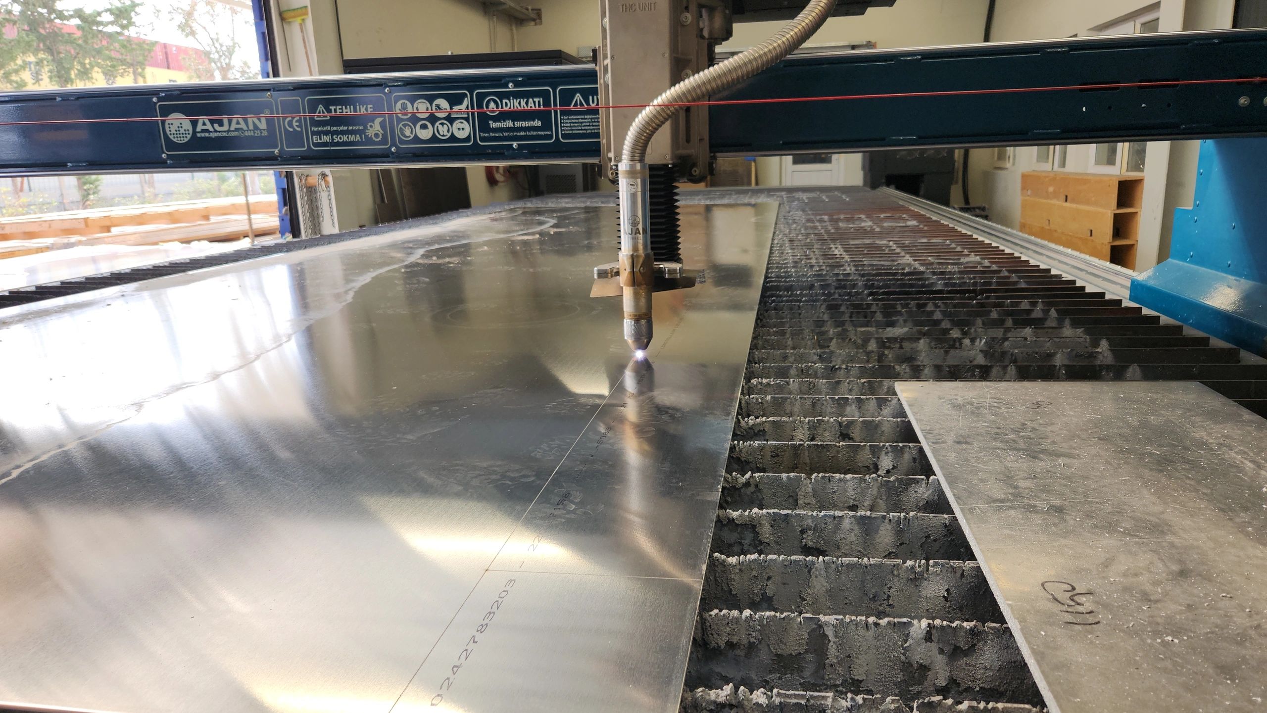 CNC plasma cutting machine processing a metal sheet in a workshop